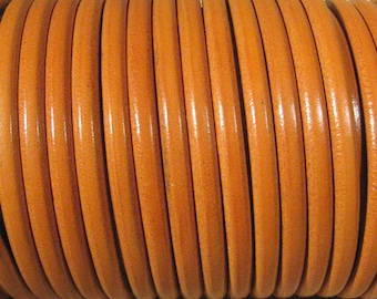 May include: A close-up of a roll of orange leather cord. The cord is smooth and has a slight sheen. It is perfect for crafting projects.