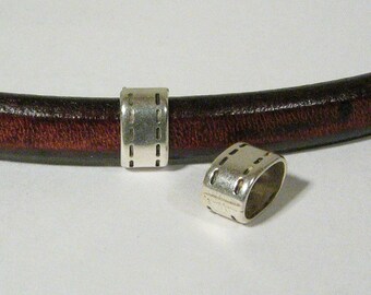 May include: Two silver metal beads with a stitched design. The beads are designed to be used on leather cord.