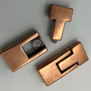 May include: Three copper-colored metal clasps for jewelry making. The clasps are rectangular in shape and have a simple design.