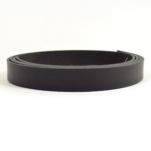 Op de afbeelding: Een rol zwart lederen band, ongeveer 2,5 cm breed.