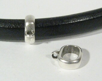 May include: Two silver metal clasps for leather bracelets. The clasp on the left is closed and the clasp on the right is open.