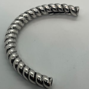 May include: A silver twisted bangle bracelet with a smooth, polished finish.