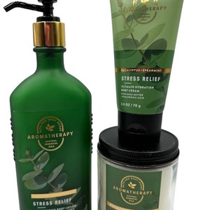May include: A set of three bath and body products in a green and white color scheme. The products are a body lotion, a body cream, and a scented candle. All three products feature the text "Stress Relief" and "Eucalyptus Spearmint" and are labeled "Bath and Body Works Aromatherapy".