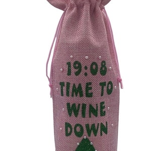 May include: Pink burlap wine bottle bag with green glitter text that reads "19:08 Time to Wine Down" and a green glitter leaf with white pearl accents.