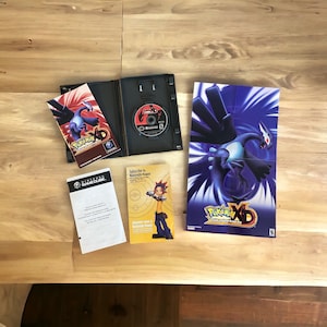 May include: A complete set of the Pokemon XD: Gale of Darkness video game for the Nintendo GameCube. The set includes the game disc, instruction manual, and a poster featuring the legendary Pokemon Rayquaza.