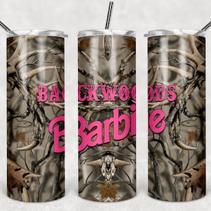 May include: A stainless steel tumbler with a camouflage pattern featuring antlers and the text "Backwoods Barbie" in pink.