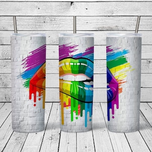 May include: Three stainless steel tumblers with a white brick background and a colorful rainbow lip design. The lips are dripping with paint.