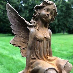 Beautiful cast iron gardenfairy sitting on a ball of flowers