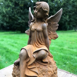 Beautiful cast iron gardenfairy sitting on a ball of flowers