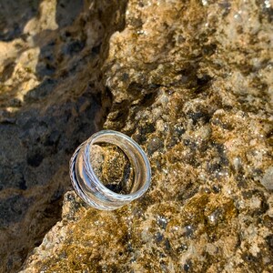 May include: Two silver rings stacked on top of each other on a brown, textured rock.