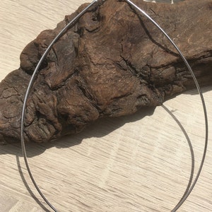 Op de afbeelding: Een zilveren slangenkettingketting op een houten oppervlak.