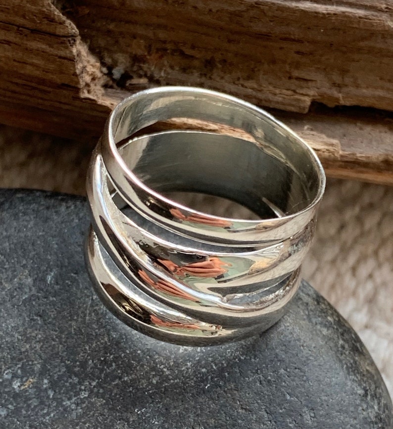 Pu&ograve; includere: Un anello d'argento con una fascia larga composta da pi&ugrave; fasce sovrapposte. L'anello &egrave; liscio e lucido.