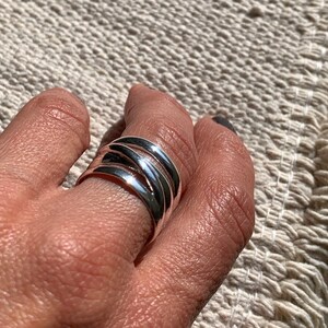 Pu&ograve; includere: Un anello d'argento con pi&ugrave; bande intrecciate e intrecciate.