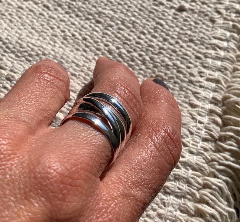 Pu&ograve; includere: Un anello d'argento con pi&ugrave; bande intrecciate e intrecciate.