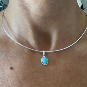 Op de afbeelding: Een zilveren ketting met een turquoise hanger. De hanger is ovaalvormig en heeft een zilveren frame.