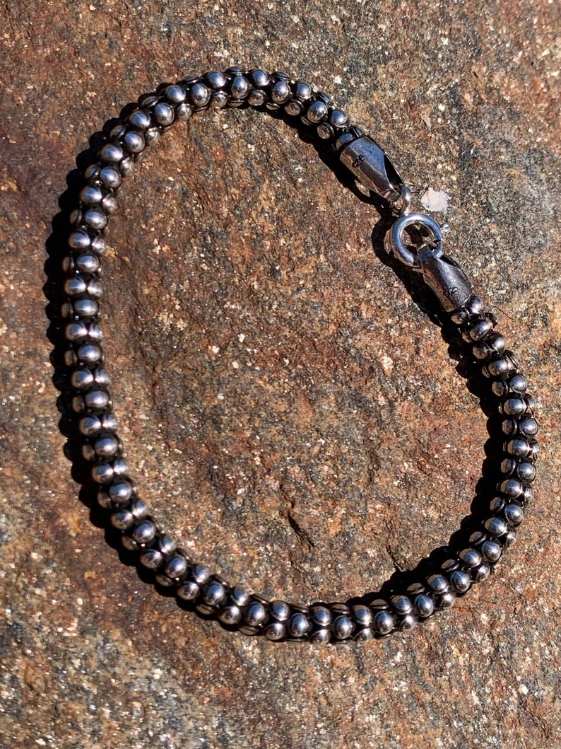 K&ouml;nnte beinhalten: Ein silbernes Armband mit Perlen und einem Karabinerverschluss.