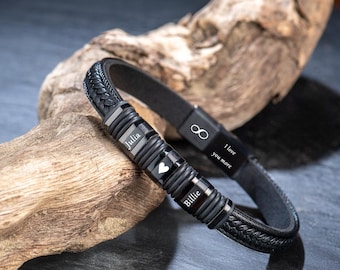 May include: Black leather bracelet with braided detailing and a magnetic clasp. The bracelet has personalised name beads, a heart charm, and the inscription "I love you more" with an infinity symbol.