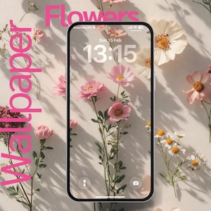 May include: A smartphone displays a floral wallpaper with pink flowers and the time 13:15. The word "Flowers" is written in pink at the top, and "Wallpaper" is written vertically on the left. Various pink and white flowers are scattered around the phone.