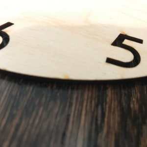 May include: Close-up of a wooden clock face with black numbers 5 and 6.