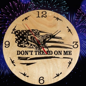 May include: A wooden clock with a red and white American flag design and the words "Don't Tread On Me". The clock face has Roman numerals and a snake design.