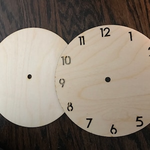 May include: Two unfinished wooden clock faces, one with numbers 1 through 12 and the other blank.