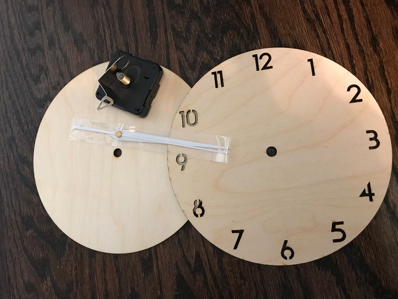 May include: Two unfinished wooden clock faces with black numbers 1 through 12, a clock mechanism, and white clock hands.