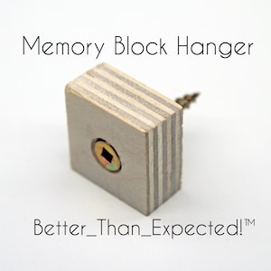 May include: A light gray wooden square hanger with a screw for hanging memory blocks. The hanger has a wood grain pattern and the text "Memory Block Hanger" is printed above it. The text "Better_Than_Expected!™" is printed below the hanger.