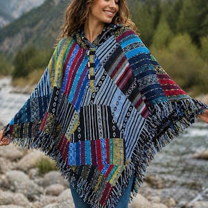 Può includere: Un poncho patchwork colorato con cappuccio e frange. Il poncho presenta una varietà di motivi e colori, tra cui blu, rosso, giallo e nero. Ha bottoni in legno e una tasca frontale. Il testo "Laxman's collection" è visibile.