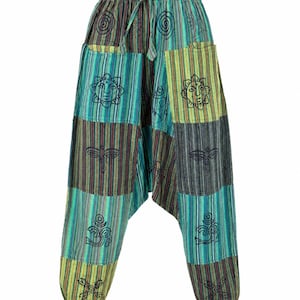 Op de afbeelding: Harembroek met een patchwork ontwerp in groen, blauw en bruin. De broek heeft een tailleband met trekkoord en zakken. Geborduurde symbolen en strepen sieren het unieke, comfortabele ontwerp.