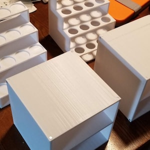May include: Four white plastic organizers for storing small items. The organizers are made of a textured plastic and have different shapes and sizes.