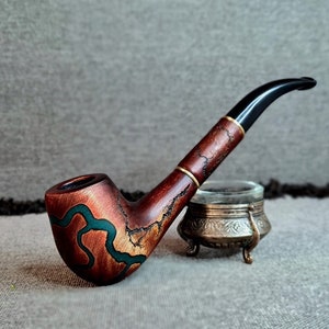 Op de afbeelding: Een houten pijp met een bruine en groene gebeitst afwerking. De pijp heeft een zwart mondstuk en een kom met een groene en bruine swirl-ontwerp.