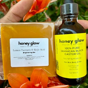 May include: A yellow bar of soap with the text "honey glow Health & Wellness Lemon Turmeric & Kojic Acid Brightening Bar" and a yellow bottle of oil with the text "honey glow Health & Wellness 100% PURE JAMAICAN BLACK CASTOR OIL Nourishing Moisturizer For Skin, Body, & Hair Cold Processed Unrefined  Herone Free 2 oz/59.1 ml"