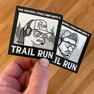 May include: Two black and white stickers with illustrations of people wearing sunglasses and hats. The stickers read "THIS MEETING COULD HAVE BEEN A TRAIL RUN" and "EETING COULD HAVE BEEN A IL RUN". The stickers are held by a hand.