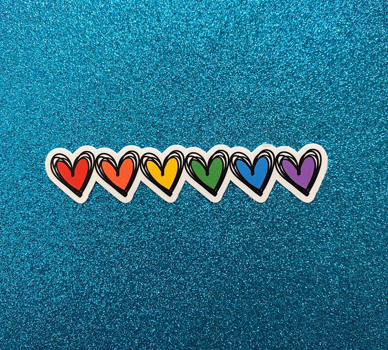 Puede incluir: Una fila de seis corazones de colores arco&iacute;ris con contornos negros. Los corazones est&aacute;n dispuestos en l&iacute;nea de izquierda a derecha, con los colores rojo, naranja, amarillo, verde, azul y morado.