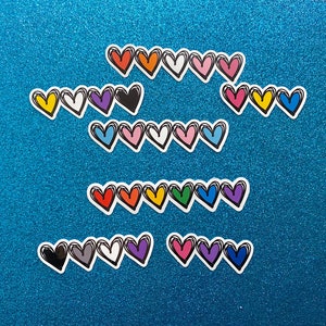 Puede incluir: Una colecci&oacute;n de pegatinas en forma de coraz&oacute;n de colores con contornos negros. Las pegatinas est&aacute;n dispuestas en filas sobre un fondo azul brillante.