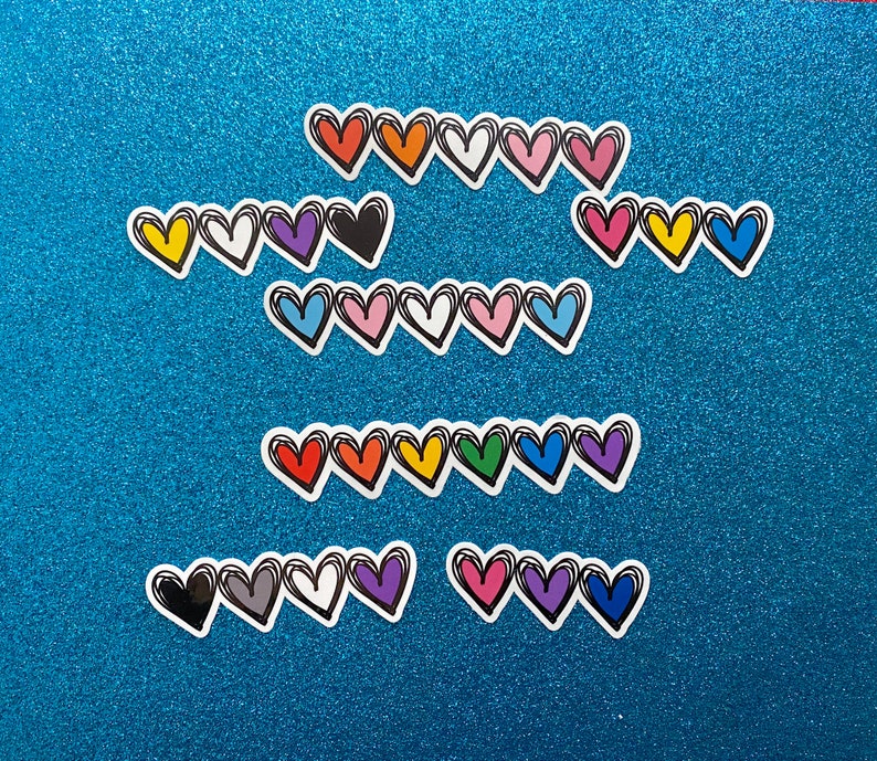 Puede incluir: Una colecci&oacute;n de pegatinas en forma de coraz&oacute;n de colores con contornos negros. Las pegatinas est&aacute;n dispuestas en filas sobre un fondo azul brillante.