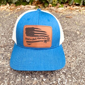 May include: A blue and white trucker hat with a brown leather patch featuring a distressed American flag and the text "United we stand, disarmed we fall".