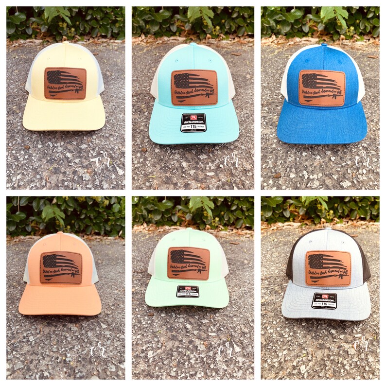 May include: Six different colored trucker hats with a white mesh back. Each hat has a brown leather patch with an American flag and the text "Hold on, God doesn't make mistakes".