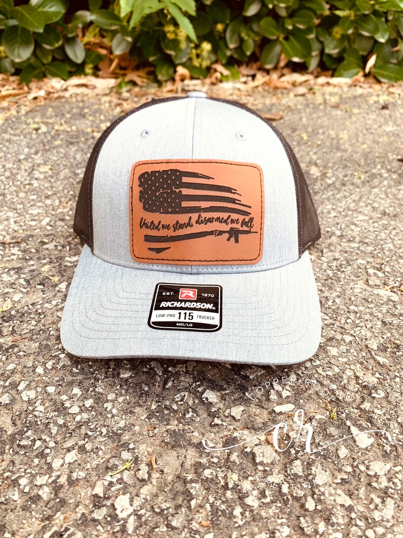 May include: A gray and black trucker hat with a brown leather patch that says "United we stand, disarmed we fall" with a silhouette of an American flag and a rifle. The hat has a Richardson 115 label.