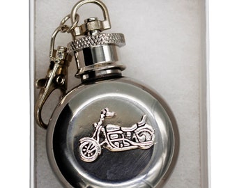 May include: A silver metal flask with a motorcycle design on the front. The flask has a screw-on cap and a metal chain attached to a ring.