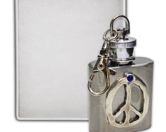 May include: A silver flask with a peace sign design and a blue gemstone. The flask has a silver cap and a silver key chain.