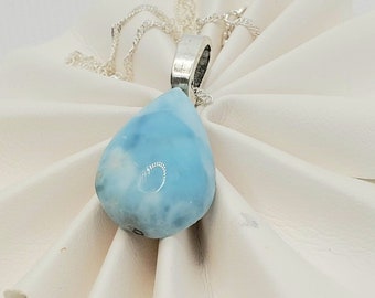 May include: A teardrop-shaped pendant necklace with a light blue gemstone and a silver chain.
