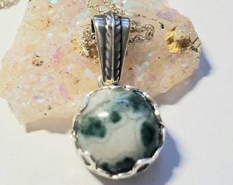 May include: A silver pendant necklace with a green and white agate stone. The stone is set in a silver bezel and the pendant is attached to a silver chain.