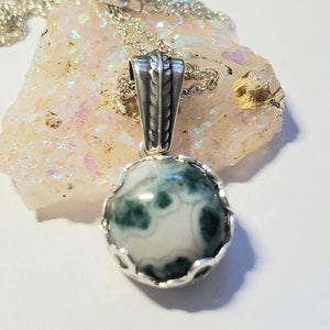 May include: A silver pendant necklace with a green and white agate stone. The stone is set in a silver bezel and the pendant is attached to a silver chain.