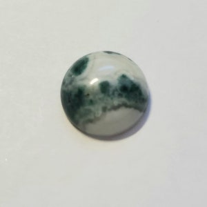 May include: A round, green and white agate cabochon with a swirling pattern.