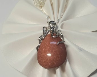 May include: A silver octopus pendant with a teardrop-shaped sunstone. The pendant is on a silver chain.