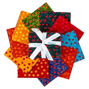 May include: A collection of colorful fabric squares arranged in a circular pattern. The fabrics feature polka dot designs in various colors, including red, orange, green, and blue. A square bundle is tied with a white ribbon that has text on it.