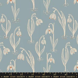 May include: A fabric with a repeating pattern of snowdrop flowers in a cream color, with orange accents, on a muted blue background. The flowers have long stems and leaves. The text "RUBY STAR SOCIETY" is at the bottom.