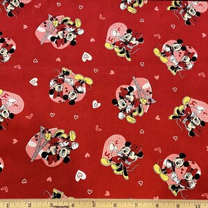 May include: Red fabric with a repeating pattern of Mickey Mouse and Minnie Mouse in various poses. The background is a solid red with small white hearts.