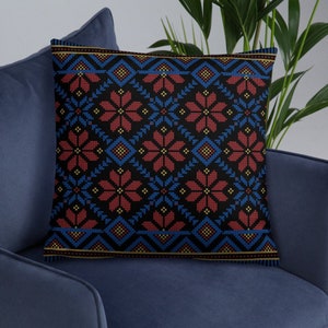 Pu&ograve; includere: Un cuscino nero con un motivo geometrico rosso, blu e giallo. Il motivo ricorda l'arte popolare tradizionale.
